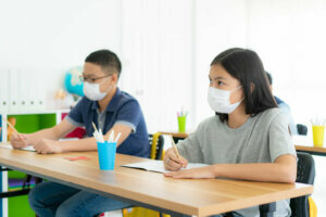 Group of Asian elementary school students wearing hygienic mask to prevent the outbreak of Covid 19 in classroom while back to school reopen their school, New normal for education concept.
