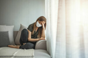 Sad lonely girl isolated stay at home in protective sterile medical mask on face looking at window