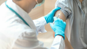World immunization week and International HPV awareness day concept. Teenager woman having vaccination for influenza or flu shot or HPV prevention vaccine with syringe by nurse or medical officer.