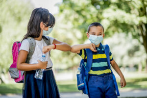 Two school children using elbow bump as an alternative handshake outdoors