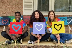 WTOP Top Kid Lucas Davila sits with one of the Rustic Love Vienna heart signs his family's nonprofit makes.