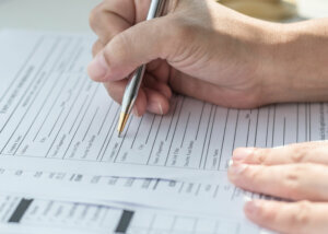 Applicant filling in company application form document applying for job, or registering claim for health insurance