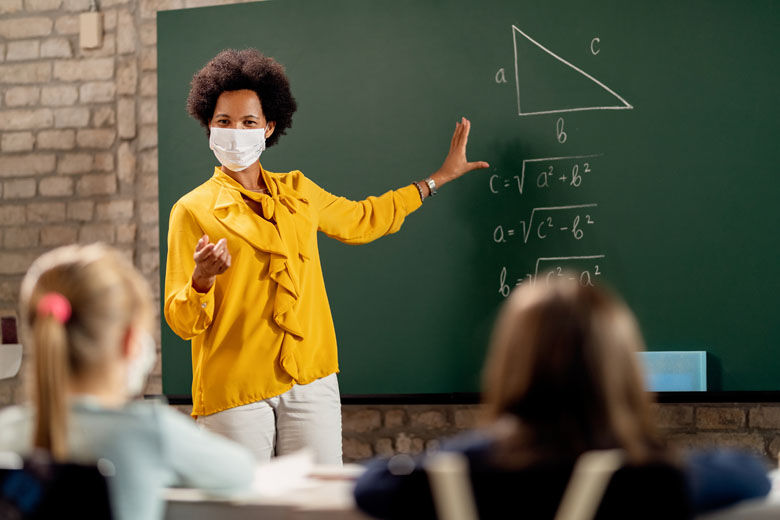 Teacher wearing face mask while explaining math lesson in the classroom.