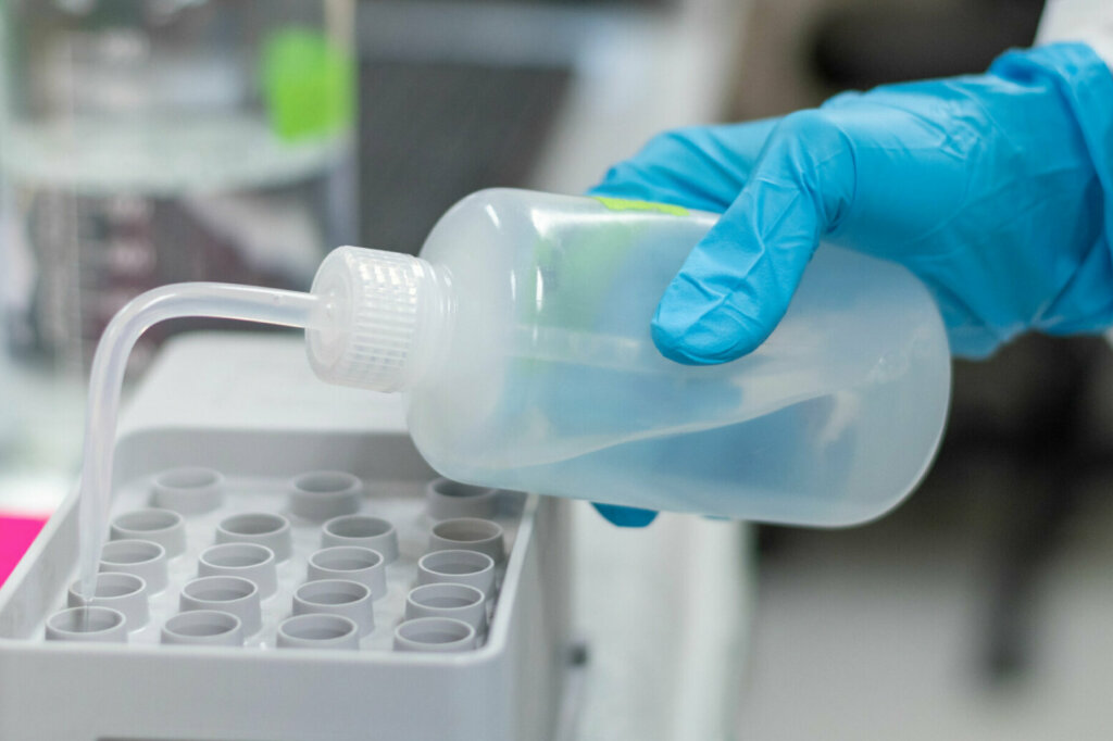 Med lab technologist using DNA sequencing equipment in science room. Chemist or scientist wearing blue medical glove working in hospital or university research laboratory.
