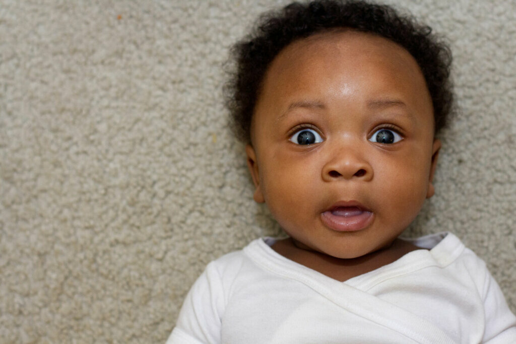 Black baby laying down looking at camera