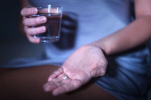 Sleeping,Pill,In,Hand.,Woman,Sitting,On,Bed,With,Medicine