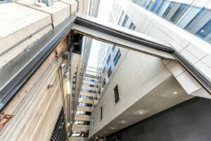 Wide angle perspective looking up of narrow alley way street road garage in city, building exterior facade office during day, architecture