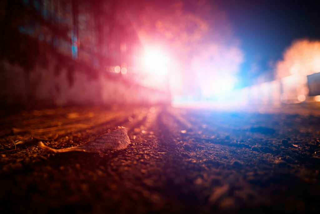 Autumn leaf on the road surface with blue and red police lights in the background