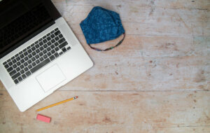 Digital learning laptop and mask on wood desk