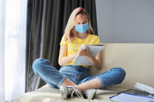 Girl student in protective medical mask studies