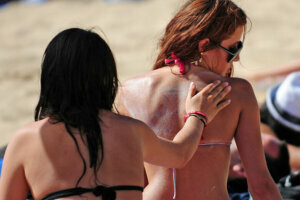 A woman spreads sunscreen on the back of