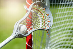 Abstract view of a lacrosse stick scooping up a ball. Sunny day
