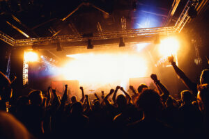 Cheering crowd of unrecognized people at a rock music concert. concert crowd in front of bright stage lights and smoke. Concert audience at music concert.