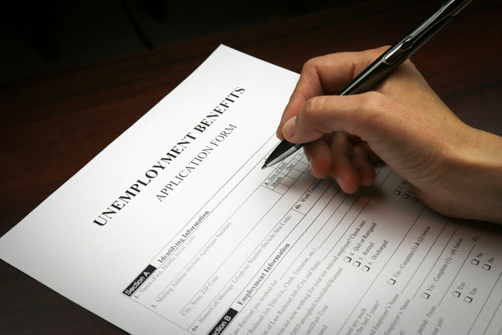 Close up of a person's hand filing social security benefits application form.