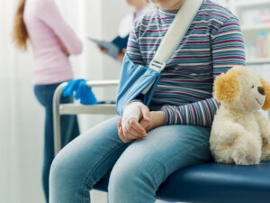 Cute girl with arm brace and teddy bear