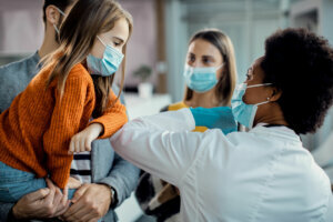 Little girl and African American female doctor elbow bumping at medical clinic.