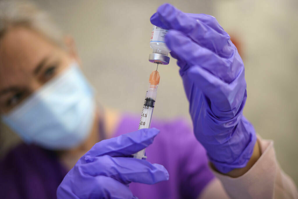 Medical professional drawing vaccine from a vial.