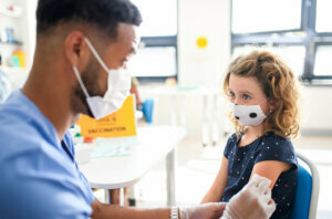 Child with face mask getting vaccinated, coronavirus, covid 19 and vaccination concept.