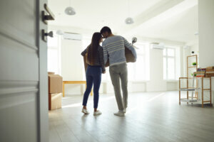 Rear view moving. Young couple family with boxes to move in a new house room.