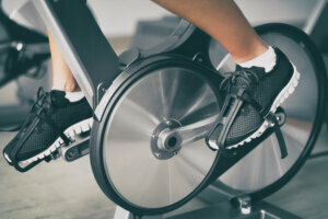 Fitness machine at home woman biking on indoor stationary bike exercise indoors for cardio workout. Closeup of shoes on bicycle