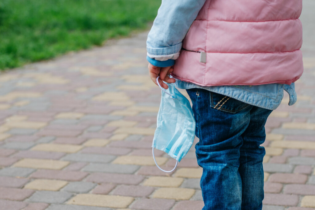 Close up of little girl holding protective face mask outside