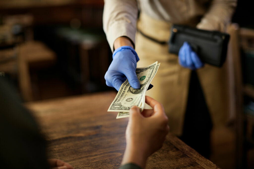 Close up of customer paying to a waitress in a cafe.