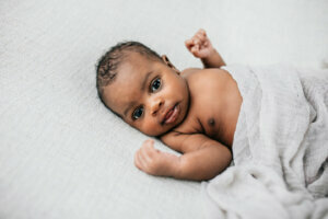 Beautiful African American newborn little boy just a few weeks old swaddled in a cream colored soft blanket with copy space