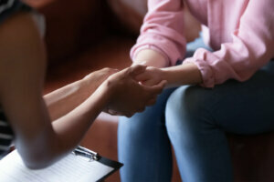 African psychologist holds hands of girl patient, closeup view