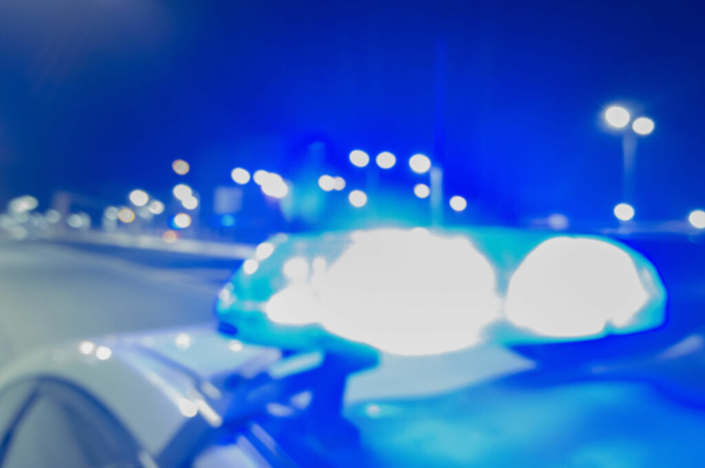 Flashing blue lights of a police car on city background, crime scene, abstract blurry image.