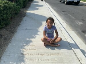 Takoma Park, Md. resident Aissatou Thiam, 7, sits next to her poem that was stamped into a sidewalk.