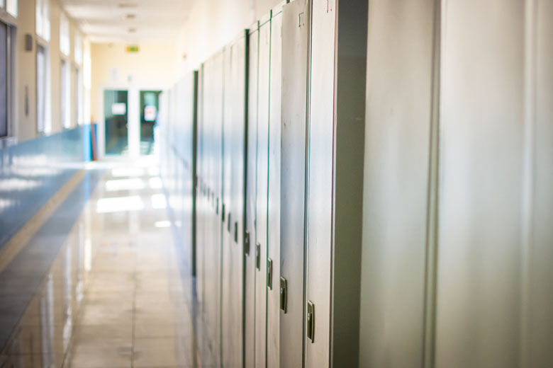 Empty hallway corridor of a high school or college closed during COVID 19 (Coronavirus). Lockers blurred into lonely hallway.