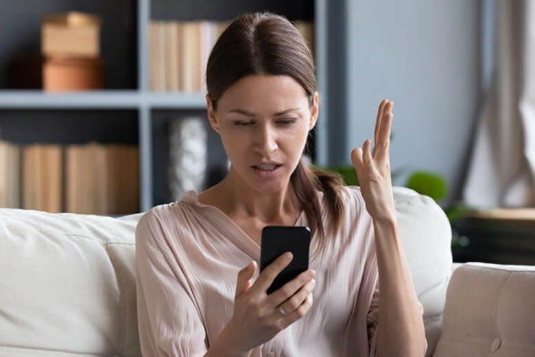 Confused angry young woman having problem with phone