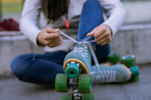 Unrecognizable woman putting her quads skates in the street
