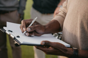 Cropped view of african american man writing something on paper in clipboard