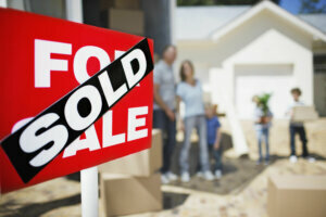 Sold sign on house with family in the background