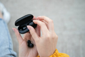 Close up of a woman taking out a black wireless earbud from his charging box. Female hands touching a portable gadget headphones. Bluetooth headset.
