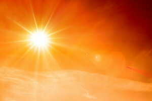Summer background, orange sky with clouds and bright sun