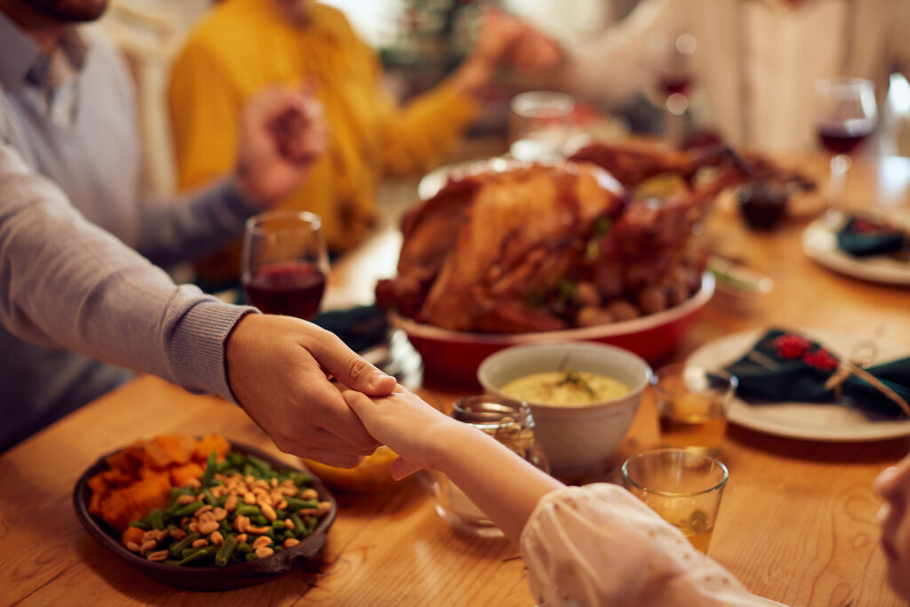 Close up of father and daughter praying during family meal on Thanksgiving at dining table.