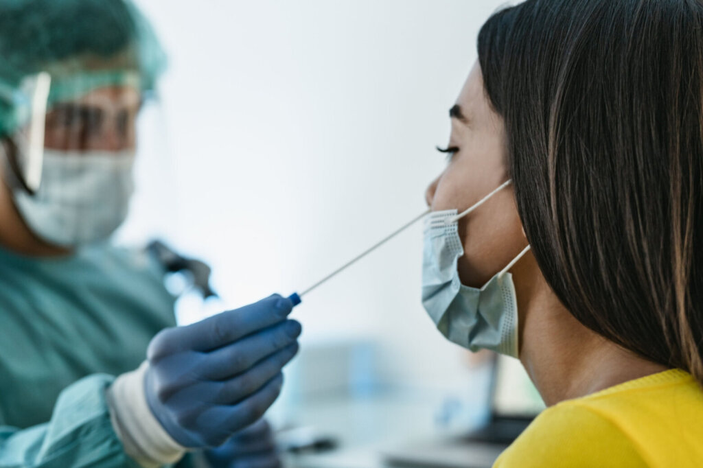 Medical worker wearing personal protective equipment doing corona virus swab on female patient Covid19 test and health care concept
