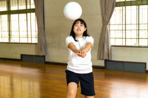 Schoolgirl practicing volleyball in the gym