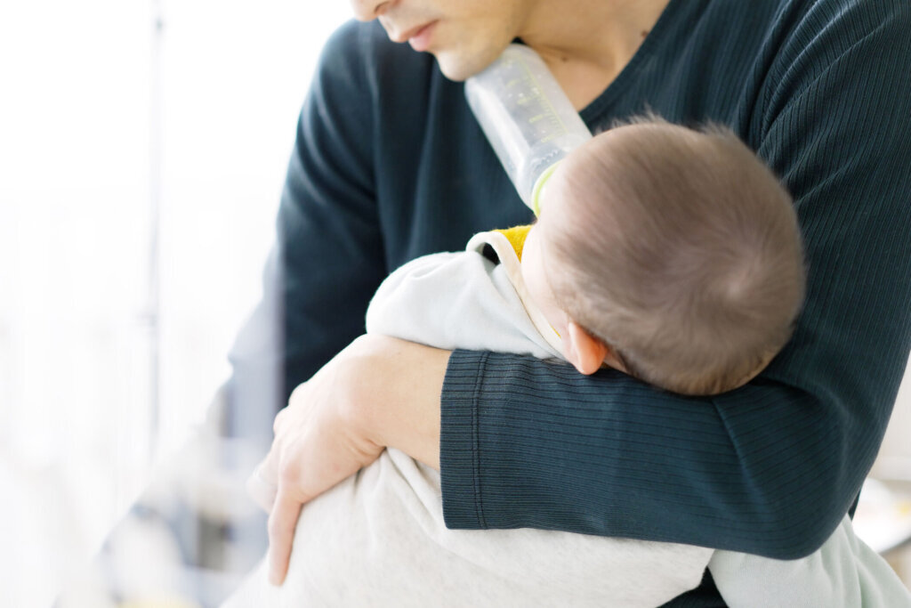 Asian man doing household chores while taking care of his baby