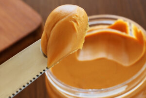Peanut butter jar and knife holding some of it