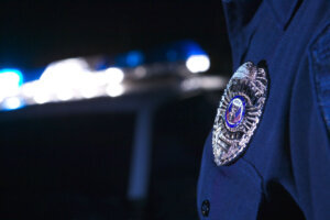 Close up of an officer's badge with the police lights on the car flashing in the background