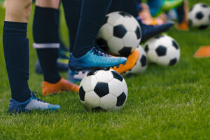 Junior Football Training Session. Players Standing in a Row with Classic Black and White Balls. Youths Practice on Soccer Field. Low Angle Close up Image of Soccer Boys. Football Education Background