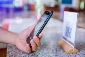 Closeup of a hand holding phone and scanning qr code. Man hand paying with qr code.