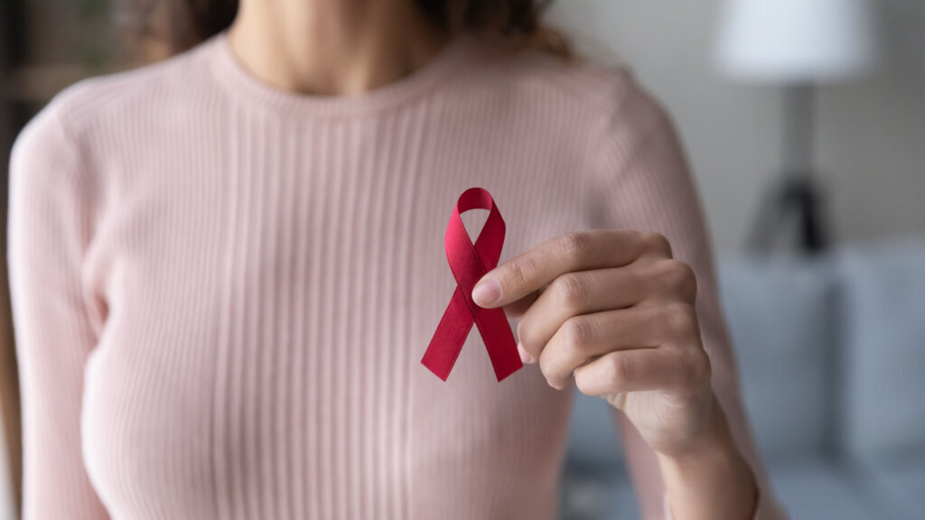 Close up female volunteer holding red ribbon in hands