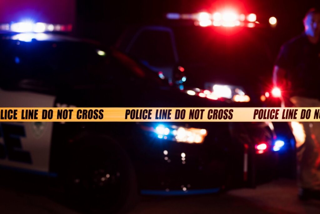 Two police officers behind crime scene tape