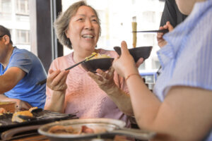 Happy mother and daughter having dinner and celebrating mothers day at restaurant