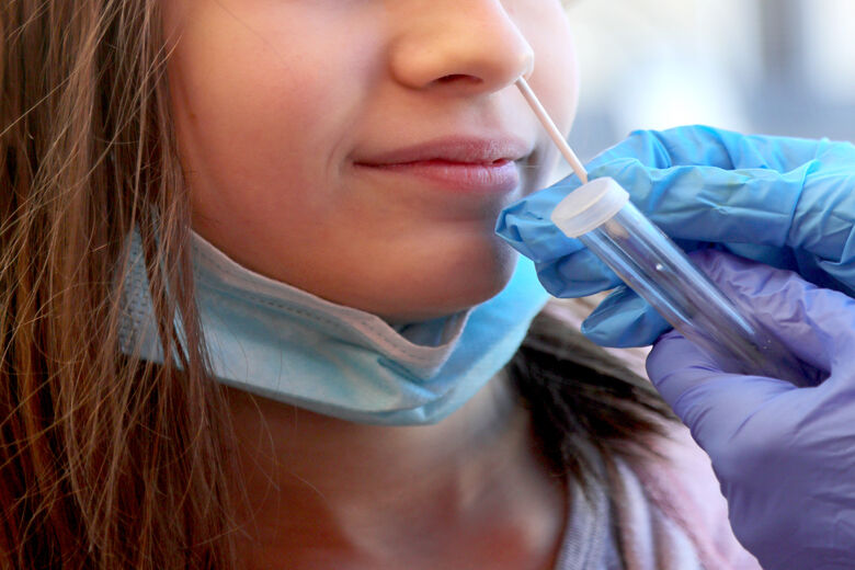 Young caucasian girl in the clinic makes a swab in the nose to look for coronavirus and the latex gloves