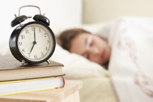 Teen girl sleeping with alarm clock nearby